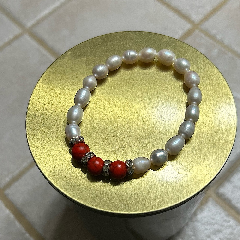 A pearl bracelet with red and gems